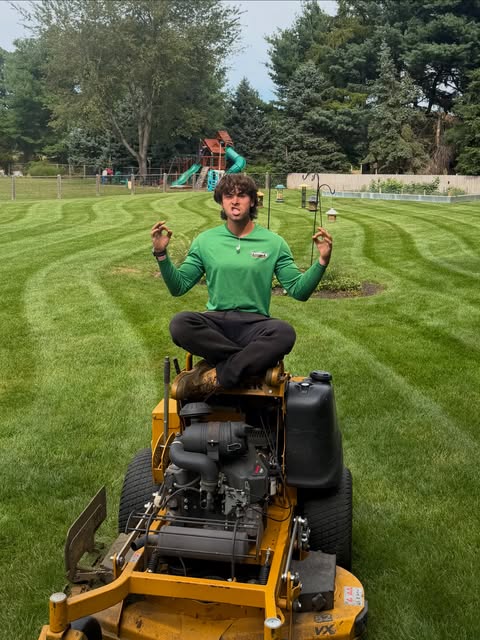 Brett sitting on his mower on a freshly cut lawn